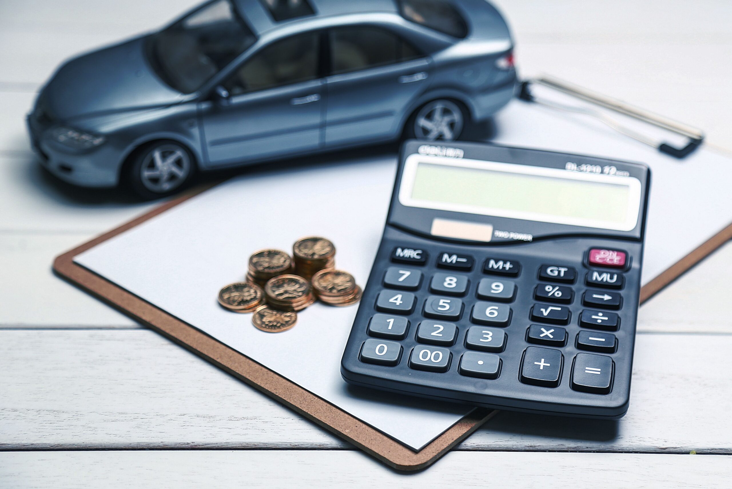 car model,calculator and coins on white table